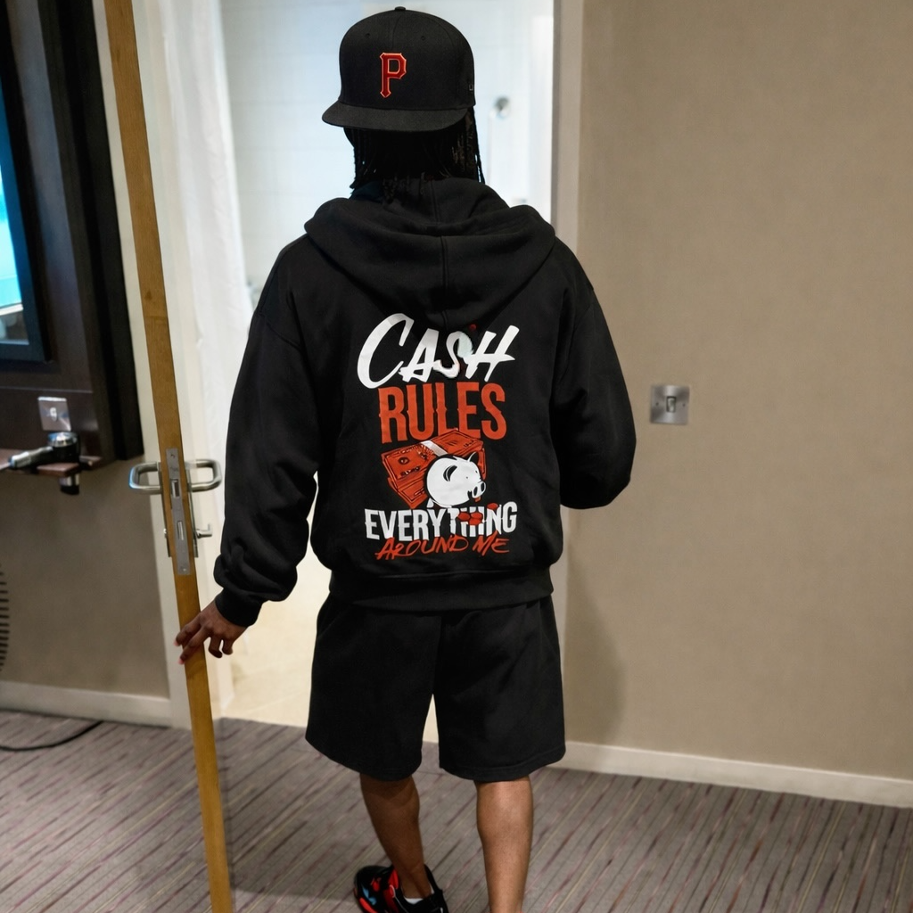 Person wearing a hoodie with 'Cash Rules Everything' text in a room.